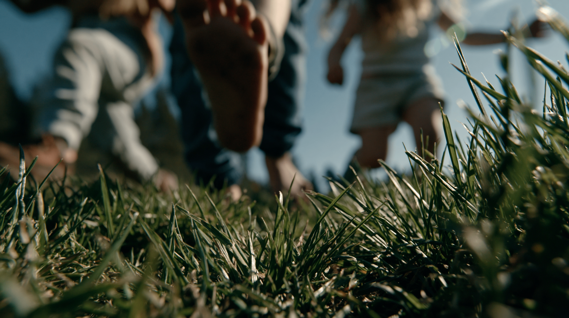 Kids running barefoot through the grass at golden hour